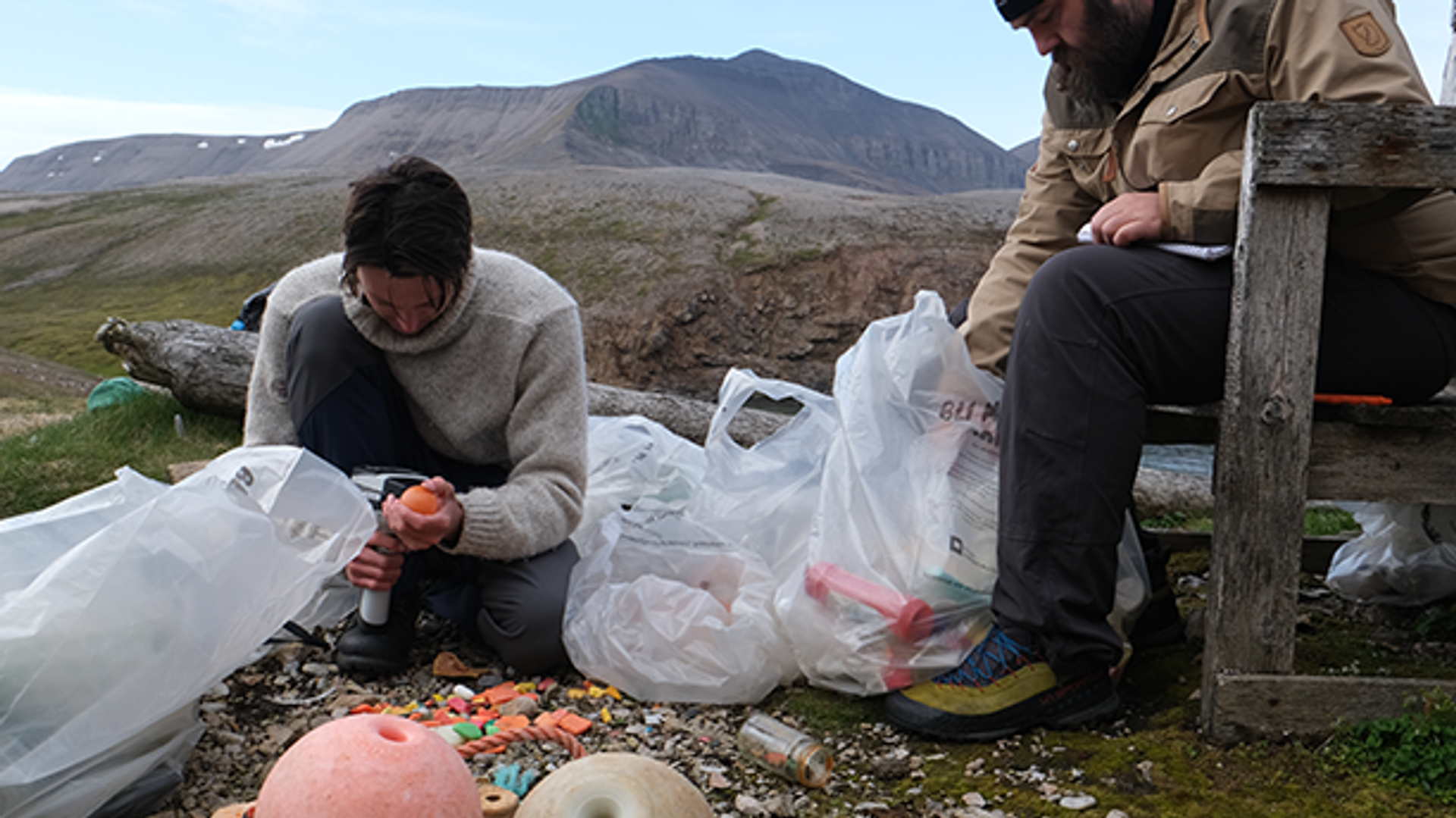 To personer går gjennom søppel og plast fra havet