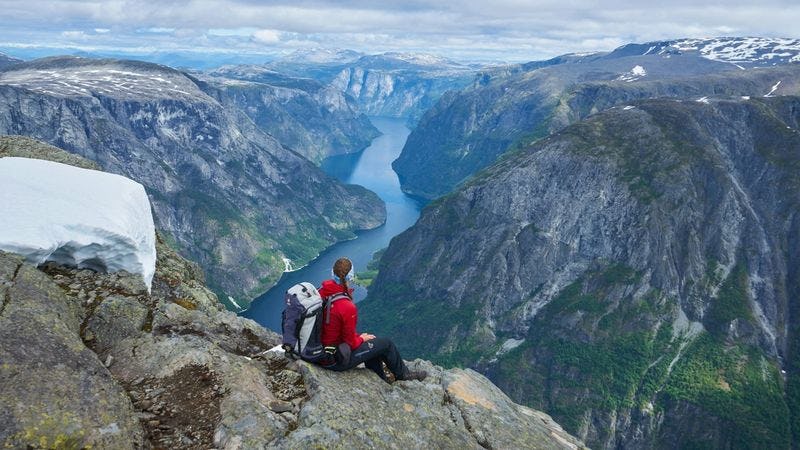 Sporty kvinne på fjelltopp ser utover landskap