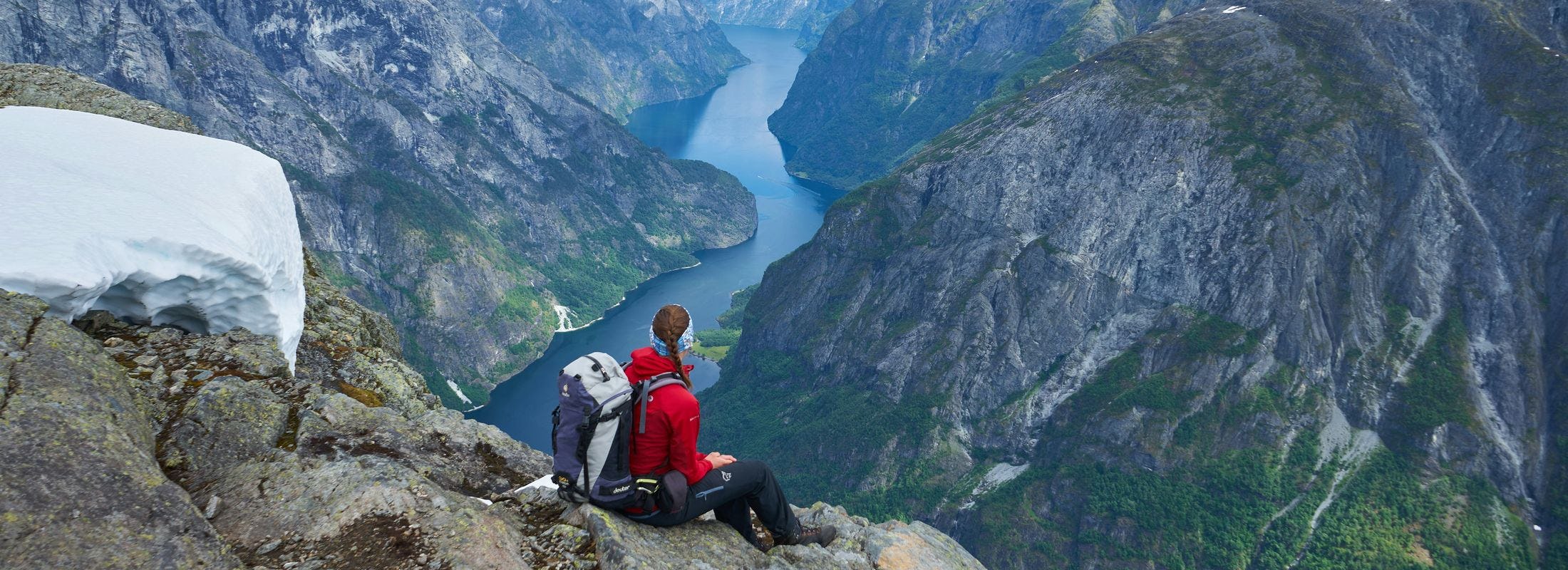 Sporty kvinne på fjelltopp ser utover landskap