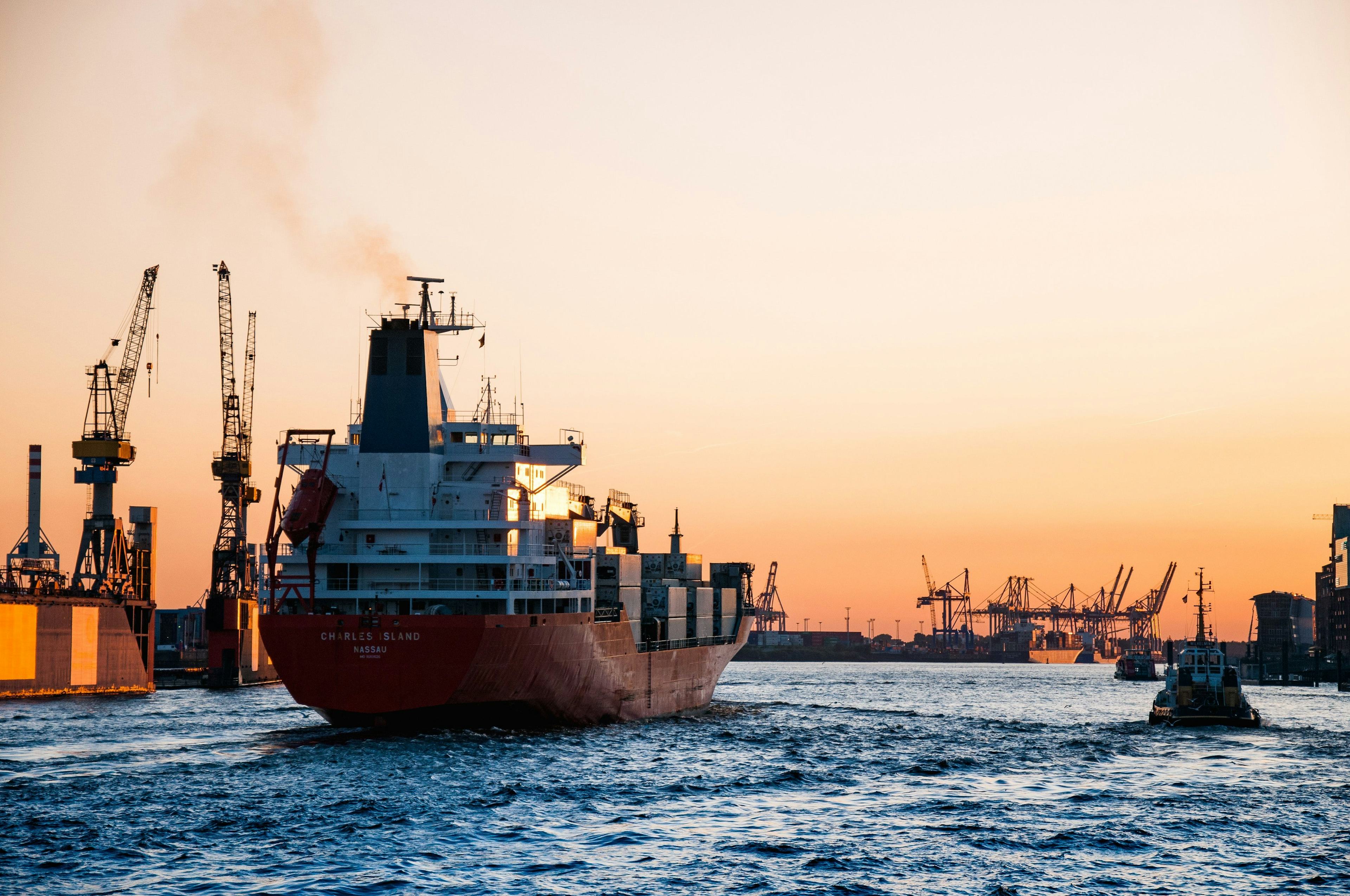 Fraktbåt på havet ved oljeplatform i solnedgang